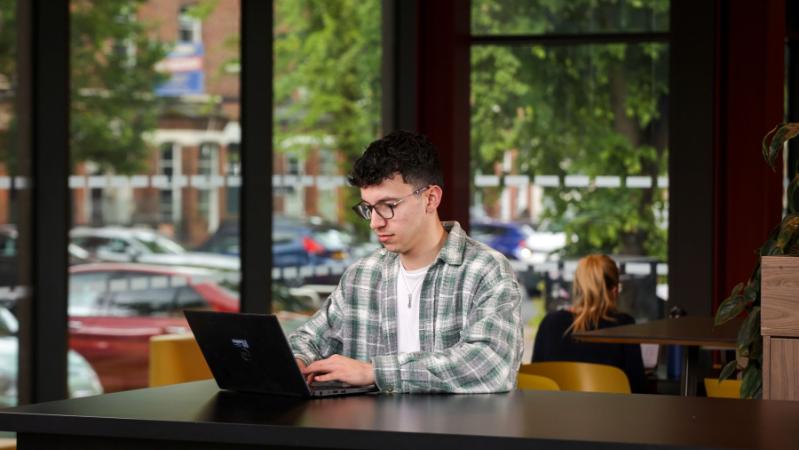 male student sitting looking at a laptop